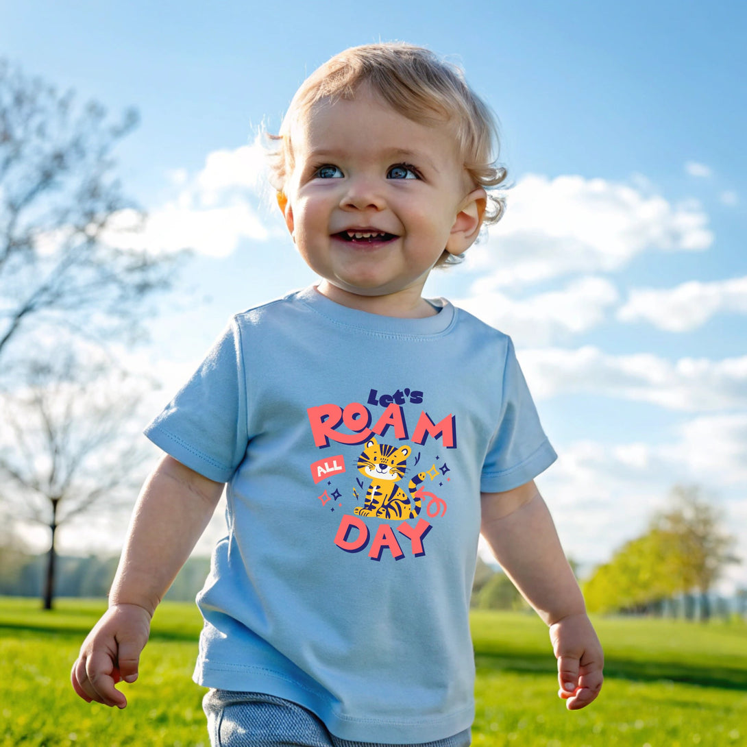 Smiling toddler wearing a blue let's roam all day shirt by CIASARA outdoors on a sunny day