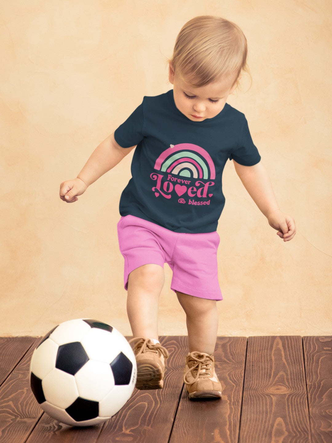Cute rainbow toddler t-shirt with pastel rainbow and text worn by toddler playing soccer