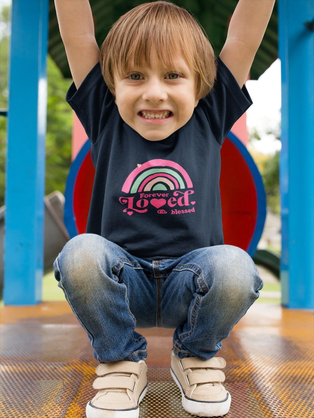 Child wearing a cute rainbow toddler t-shirt with pink and green design playing outdoors