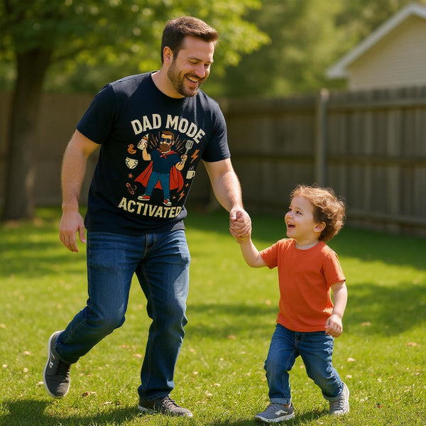 Man wearing dad mode activated t-shirt playing outside with young child in a grassy backyard