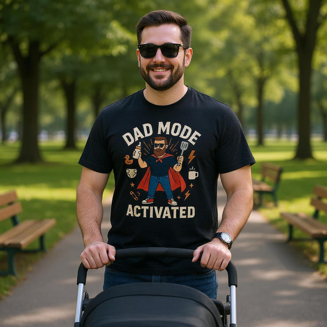 Man wearing black dad mode activated t-shirt by CIASARA pushing a stroller in a park